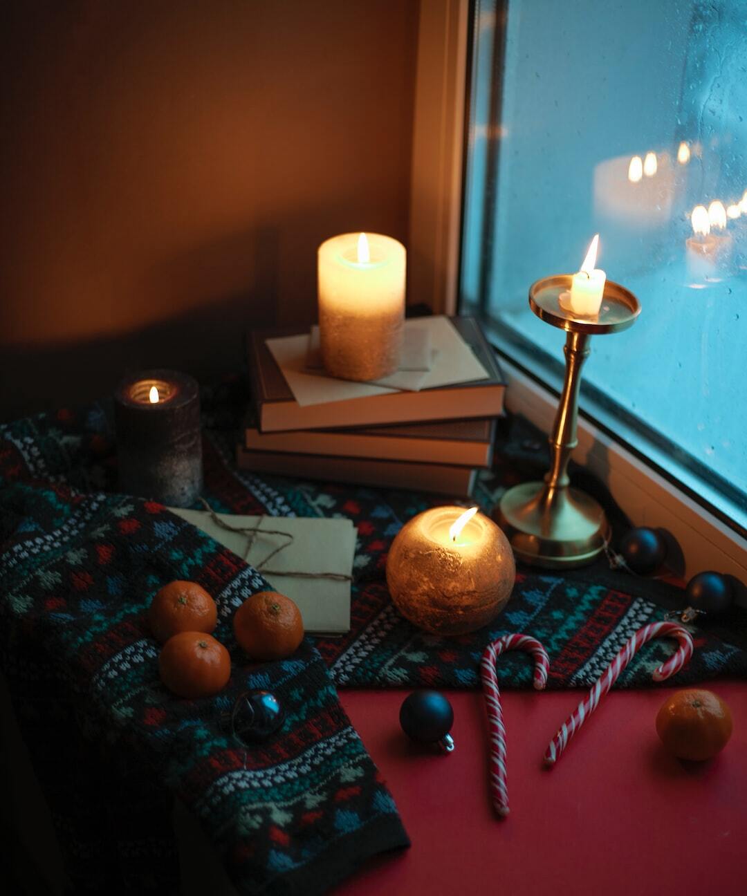 a table topped with books and candles next to a window